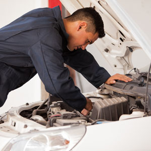 Young mechanic working on a car engine at an auto shop